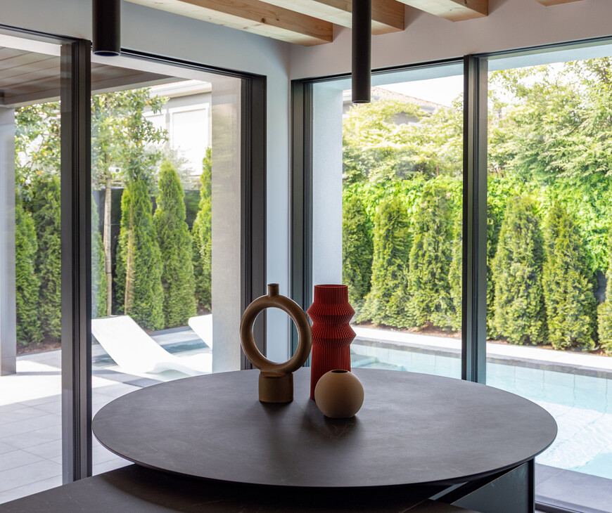 Cucina total black con penisola e piano snack in Laminam Nero Greco in ambiente luminoso con grandi vetrate sulla piscina